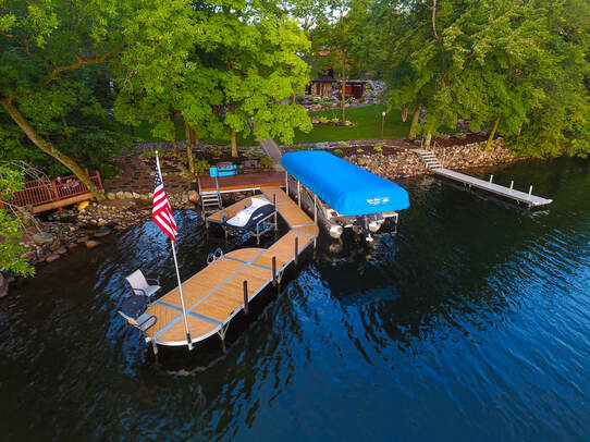 Lake Area Docks & Lifts ShoreMaster RS4 sectional dock with wood grain aluminum (Cedar look) decking, vertical bumpers, DVS vertical lift with blue canopy, PWC Lift, and american flag 